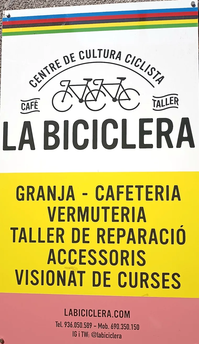 Placa del carrer de La Biciclera: Centre de Cultura Ciclista, cafè i taller, amb el llistat de serveis sobre fons groc.